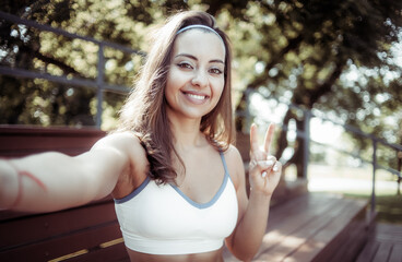 Young smiling athletic woman showing v gesture outdoors