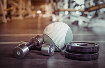 Obraz na płótnie Canvas Metal dumbbells, barbell discs and medicine ball on the gym floor. Fitness, bodybuilding and functional training equipment