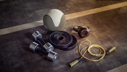 Metal dumbbells, barbell discs, kettlebell, skipping rope and medicine ball on the gym floor. Fitness, bodybuilding and functional training equipment - obrazy, fototapety, plakaty