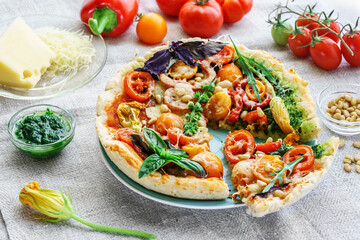 Summer vegetarian pizza with edible flowers and pine nuts