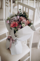 gift chic bouquet from guests in an elegant package lying on a chair at a wedding ceremony