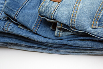 Lots of jeans pants in a stack. Denim background.