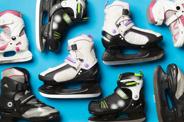 Many ice skates on color background, top view