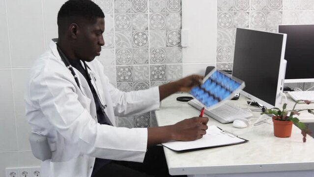 an American doctor carefully examines the MRI images making notes of the record. Modern medicine in lagging countries.