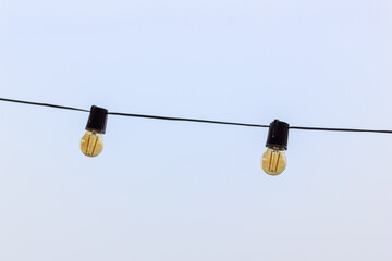 Two light bulbs suspended in the air connected by a light cord, ambient light.
