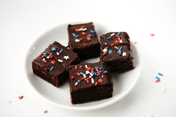 Chocolate fudge brownies with patriotic red blue white sprinkles on white background