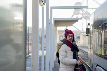 Adult woman with wool cap, waits at the tram station in Brussels to go to work. In the background the atomium