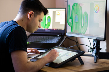 Young man drawing on a digital tablet at home. Young man working from home as graphic designer.