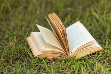 Open book on green grass in a field background concept for reading, relaxing and recreation