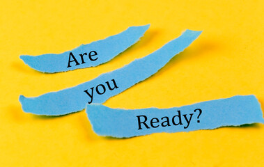 ARE YOU READY text on a blue pieces of paper on yellow background, business concept