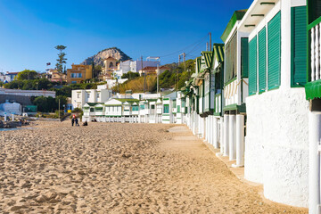 Obraz premium Prespective view of the fishermen's huts with the town of Garraf in the background of the beach. Catalonia, Spain.
