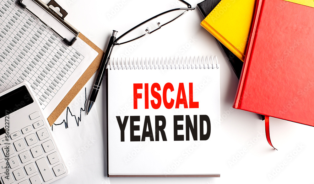 Poster fiscal year end text on notebook with clipboard and calculator on white background