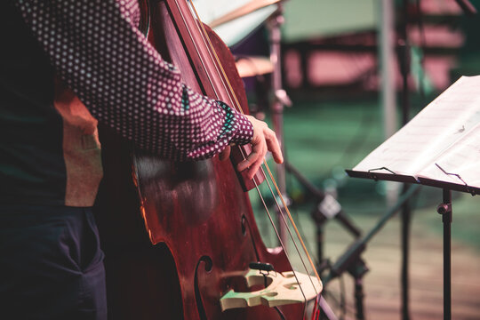 Concert view of contrabass violoncello player with musical band during jazz orchestra band performing music, violoncellist contrabassist cello jazz player on stage