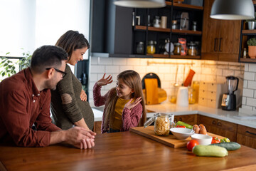 Excited little girl is grimacing with her hands, telling an imaginary story to her baby brother in...