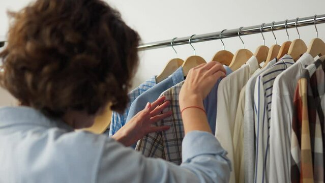 Looking for clothes on a hanger clothes rack girl looking for fashion clothes in a warehouse, Fashion clothes on wooden hangers in a store, wardrobe garments in the house clothing with things
