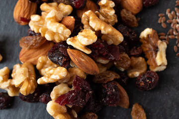 Macro photo of a mixture of nuts and dried fruits. Various nuts and berries. Top view on a black background.