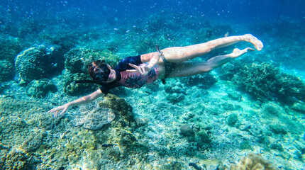 Naklejka na ściany i meble Happy woman with snorkeling mask and dive underwater in coral reef. Travel activity and water sports