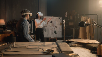 Tailors wearing VR headset with wireless controllers. They working in luxury atelier or tailoring workshop and creating weeding suit in virtual reality. Concept of technologies of future in business.