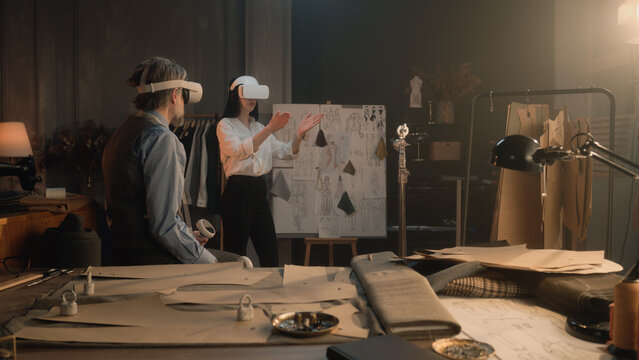 Tailors wearing VR headset with wireless controllers. They working in luxury atelier or tailoring workshop and creating weeding suit in virtual reality. Concept of technologies of future in business.