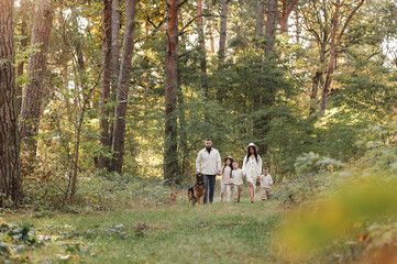 Fototapeta premium Happy playful family runing in park with pet. Young mom, dad having fun with three kids and big dog outdoors. Parents with children holding hands. Active lifestyle parenthood concept. Happy childhood