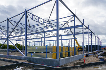 Fototapeta premium Steel structure framework building and stacks of sandwich panels for the facade covering