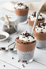 Chocolate mousse chia pudding snacks topped with whip cream and chocolate balls.
