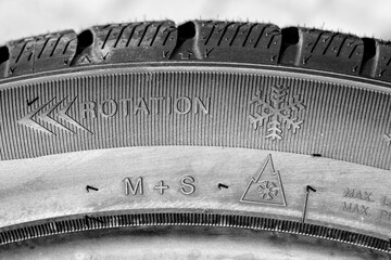 Side view of new winter tire with snowflake symbol, mud and snow and rotation direction symbols