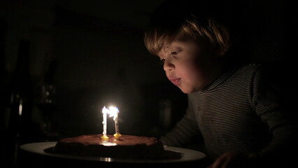 Cute child blowing birthday candles. Toddler boy celebrates anniversary, relighting magic candle