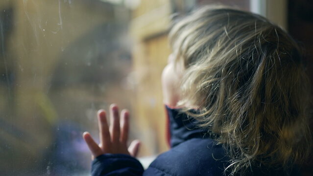 Baby toddler standing by window looking out. Child wanting to go outside