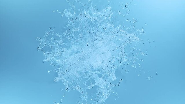 Super slow motion of splashing water shape on blue background. Filmed on high speed cinema camera, 1000fps. Top view shot.