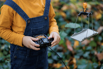 Close up of little boy controls the radio remote control in the autumn sunny weather. Child controls the construction crane using a remote control © Pokhodzhay