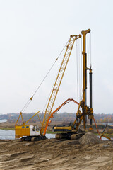 The work of cranes and other equipment at the construction site of the bridge across the river