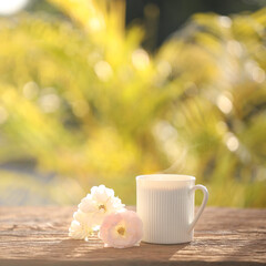 White coffee mug and roses on wooden table outdoor