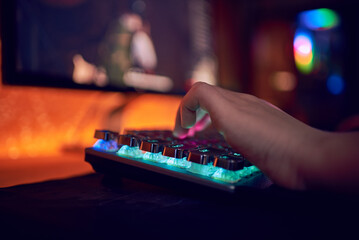 Close Up Hands Shot Showing a Gamer Pushing the Keyboard Buttons while Playing an Online Video Game. Keyboard Led Lights. Room is Dark.