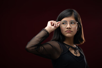 12 year old Mexican  girl portrait isolated on red background wearing glasses