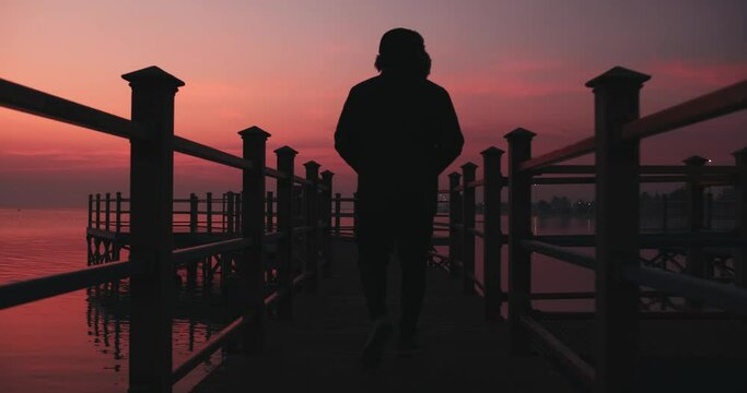 silhouette of a person in pier at sunrise.