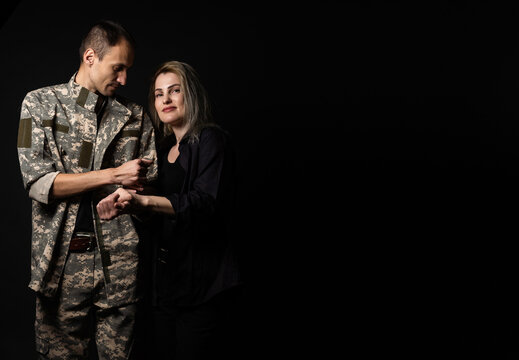 military man and his wife on a black background