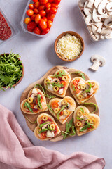 Heart shape mini pizzas on wooden board for Valentines day holiday, top view