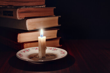 Learning by candlelight, reading in a dark room lit only by candles. In the village without electricity. Candlelight illuminates the dark room of the village house with books on the table. Blackout. 