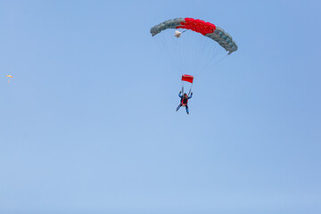Skydiver with a little canopy of a parachute on the background a blue sky, close-up. Skydiver under...