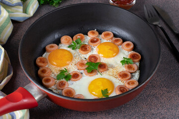 Fried eggs with sausages and fresh parsley in pan on brown background, Close up