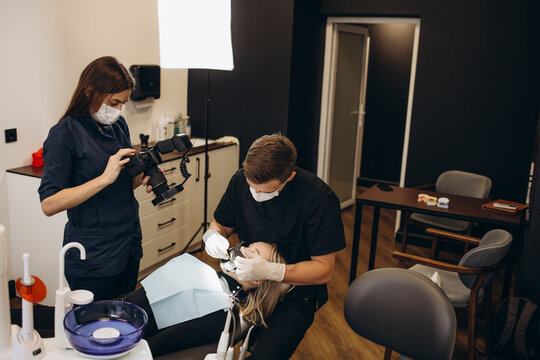 Dentist at work, dental clinic. Young woman doctor taking pictures of patient's teeth and jaw after successful treatment