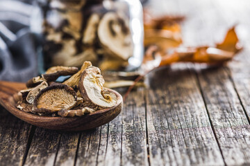 Sliced dried mushrooms in wooden spoon on wooden table.