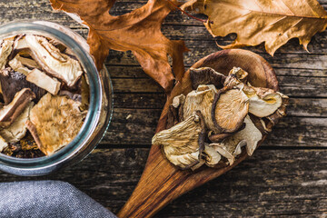 Sliced dried mushrooms in wooden spoon on wooden table. Top view.