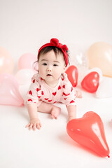 Obraz na płótnie Canvas baby with valentine's heart shaped balloons