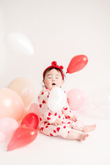 baby with valentine's heart shaped balloons