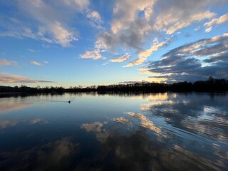 Wolken spiegeln sich im klaren Wasser eines Sees