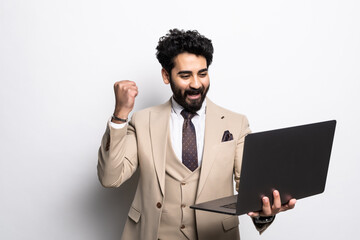 Business. Business man arab winning online, rejoicing with fist pump, holding laptop and triumphing, standing over white background