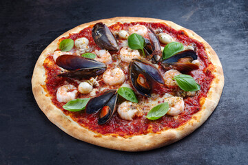 Traditionelle italienische Pizza frutti di mare Riesengarnelen, Miesmuscheln und Calamaretti serviert als close-up auf einem rustikalen Board 