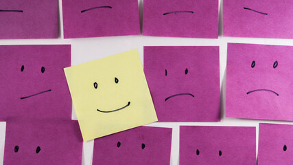 Uhhappy faces with one happy face on paper office sticky note - obrazy, fototapety, plakaty